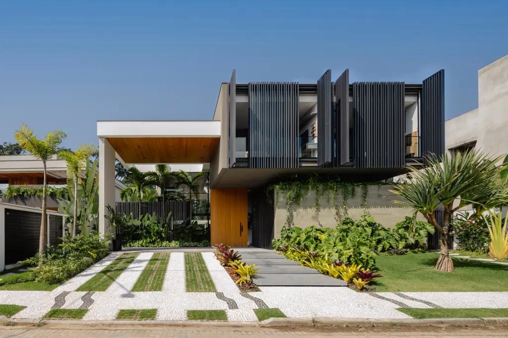 Fachada moderna com paisagismo tropical e vegetação integrada.